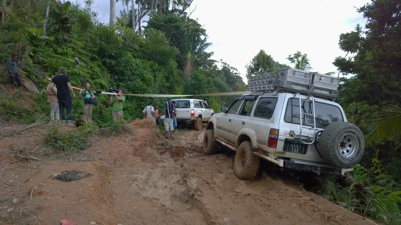 Film crew and 4x4 vehicles on a muddy forest track in Madagascar