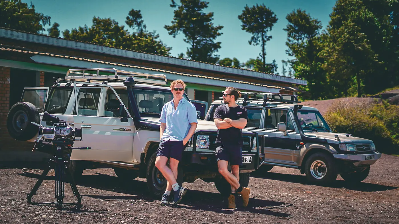 Crew members with a cinema camera beside two 4x4 vehicles in Madagascar