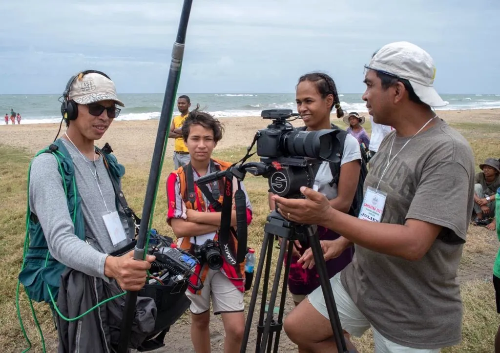 Cinéroutes crew with camera and boom microphone on a beach in Madagascar