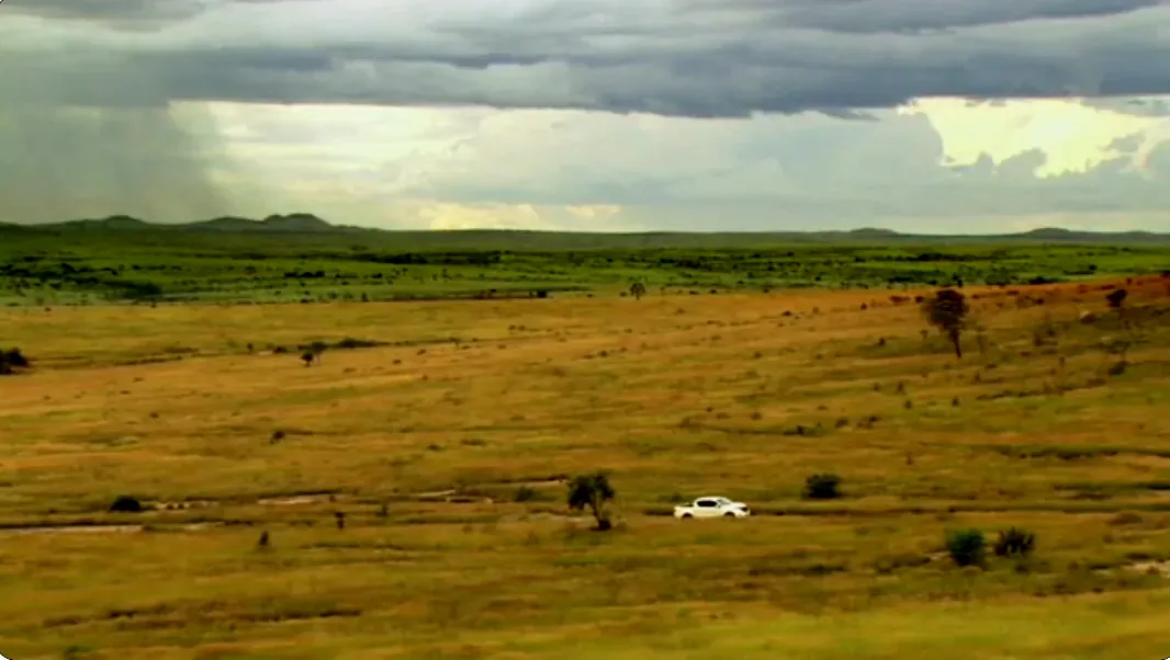 Pickup truck crossing open grassland under storm clouds in Madagascar, Extreme World with Ross Kemp