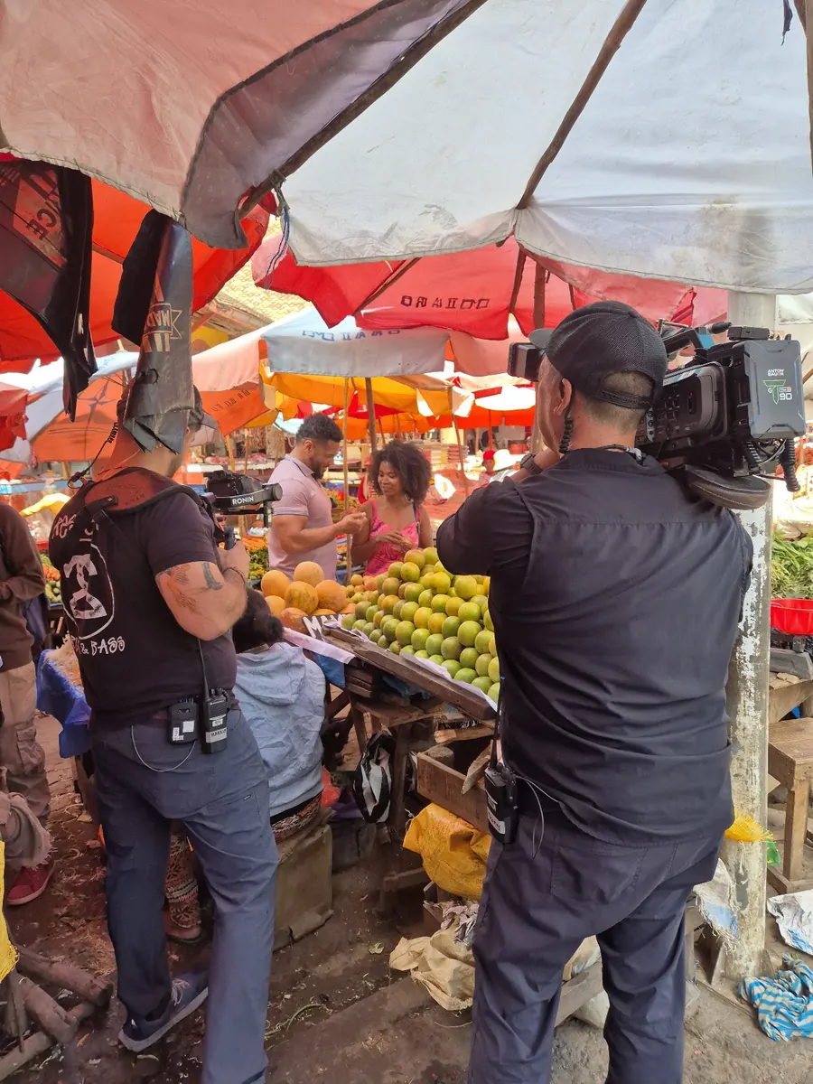 Équipe TV filmant des présentateurs devant un étal de fruits sur un marché coloré à Madagascar