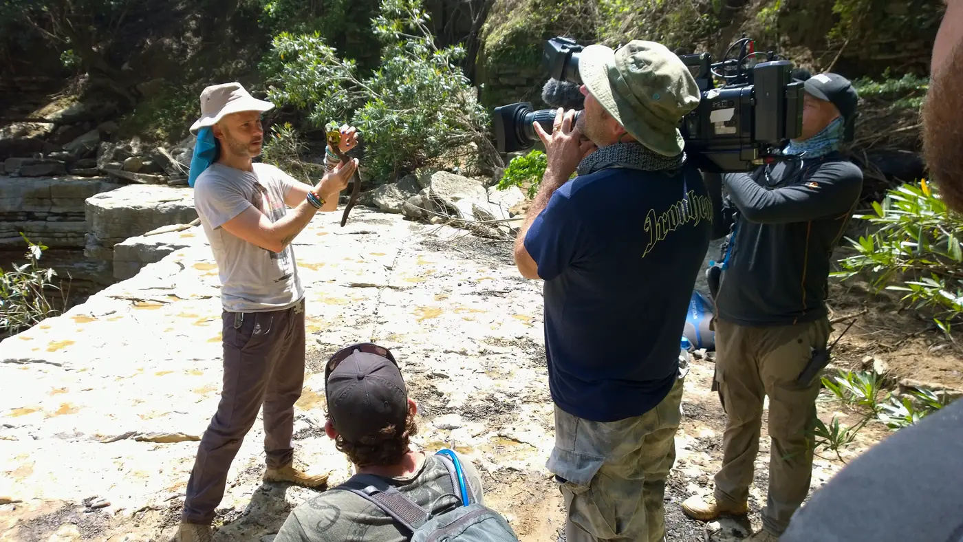 Équipe TV filmant un présentateur tenant un caméléon dans un canyon à Madagascar
